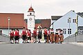 Foto aus dem Jahr 2027: Die Dollnsteiner Blaskapelle überquert in traditioneller Tracht zu Fuß die Altmühlbrücke in Dollnstein. Die Gruppe besteht aus Frauen und Männern, einige tragen Musikinstrumente wie Trompete und Tuba. Im Hintergrund ist die we